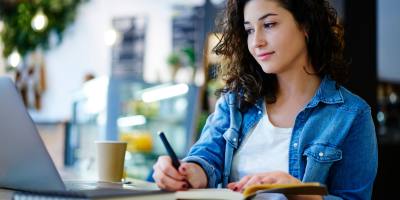 photo of woman in front of open laptop with pen and paper