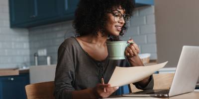 image of woman with glasses in front of laptop with paper and pen