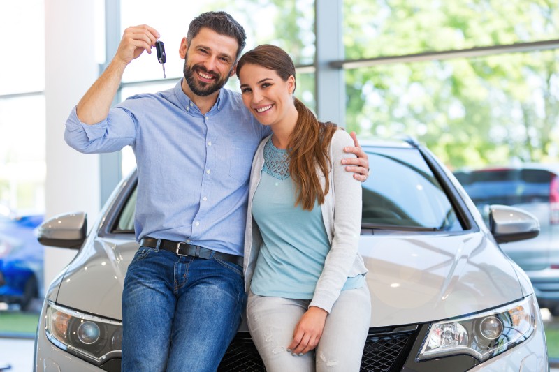 Happy couple holding the keys to their new car