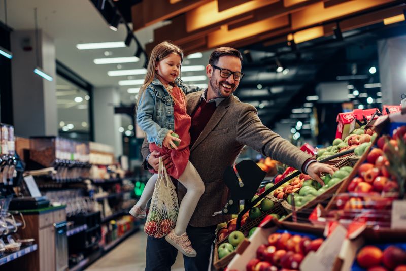 Father and daughter buying apples in grocery store