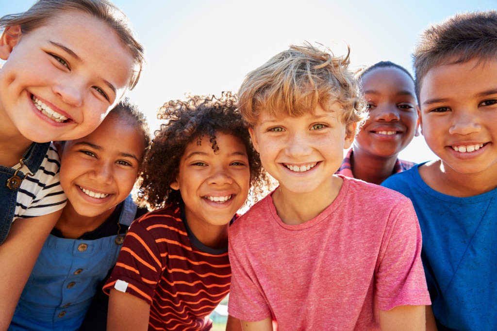 Close up of pre-teen friends at a park smiling at the camera